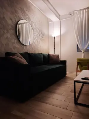 a black couch in a living room with a mirror at Apartman 57 in Vračar (historical)