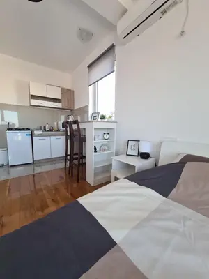 a bedroom with a bed and a kitchen with a table at Jordan Apartment - City Center in Belgrade