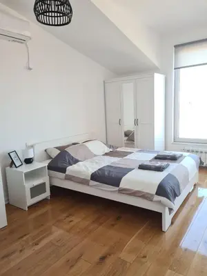 a white bedroom with a large bed and a window at Jordan Apartment - City Center in Belgrade