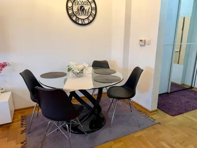 a table with four chairs and a clock on the wall at Belgrade Apartment 2 in Zvezdara