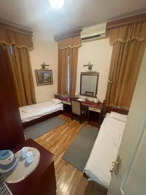 a room with two beds and a table and a mirror at Traveling Actor Skadarlija in Belgrade