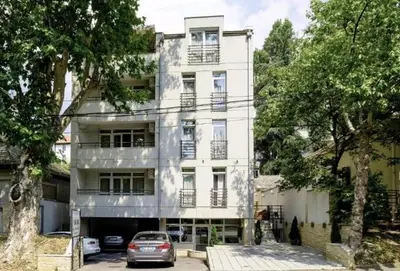a white building with a car parked in front of it at Bulevar Star Apartment in Belgrade