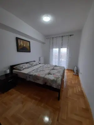 a bedroom with a bed and a wooden floor at Apartman Green wood in Arandjelovac