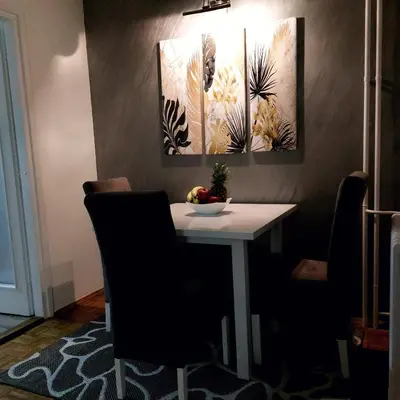 a dining room table with chairs and paintings on the wall at Apartman 22 in Belgrade