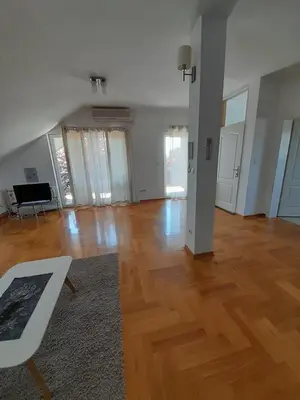an empty living room with wooden floors and windows at Apartment Ken in Surčin
