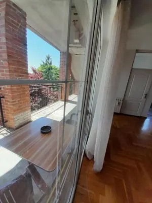 a glass room with a table and a balcony at Apartment Ken in Surčin