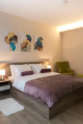 a bedroom with a large bed and a green chair at Galaxy Apartments in Belgrade