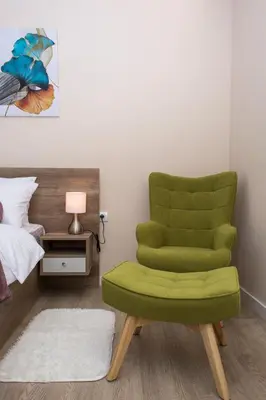 a green chair in a bedroom with a bed at Galaxy Apartments in Belgrade