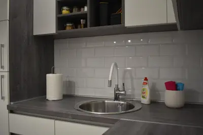 a kitchen counter with a sink and white cabinets at Damun in Belgrade