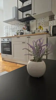 a white vase with purple flowers on a table in a kitchen at Apartment Major in Belgrade