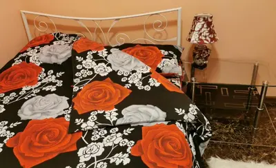 a bed with a black and white blanket with red roses at Mici Luxury Apartments in Ledine