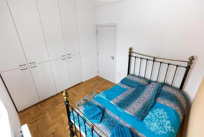 a bedroom with a bed with blue sheets and white cabinets at Mici Luxury Apartments in Ledine