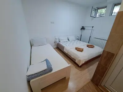 a bedroom with two beds and a bench in it at Apartmani MilaMi #1 in Belgrade