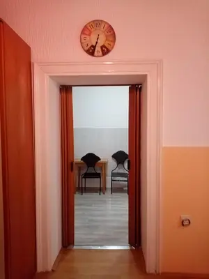 a clock on the wall above a hallway with two chairs at Apartment Anna in Belgrade