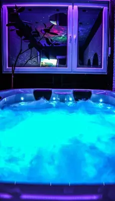 a hot tub with blue lights in front of a window at Aurora Lux Spa Smart apartments in Belgrade