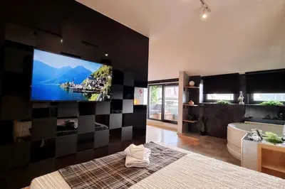 a bathroom with a large tv on a wall with a tub and a bath tub at CHILLA MILLA in Sajmište