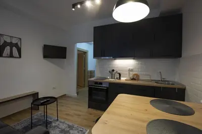 a kitchen with black cabinets and a wooden table at Belgrade apartment Bulevar in Belgrade