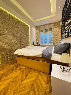a bedroom with a large bed and a brick wall at The Bohemian Residence in Belgrade