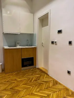 a kitchen with a wooden floor and a white door at The Bohemian Residence in Belgrade