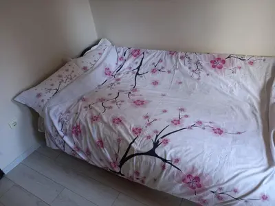 a bed with a white blanket with pink flowers on it at Sofia Apartment in Surčin