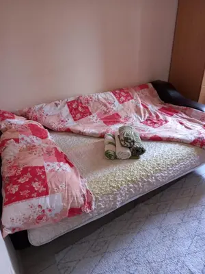 an unmade bed with shoes on the bottom of it at Sofia Apartment 2 in Surčin