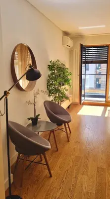 a living room with two chairs and a table and a mirror at Apartment SUN CITY 2 in Belgrade