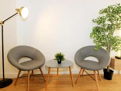 two chairs and a table with a lamp and a plant at Apartment SUN CITY 2 in Belgrade