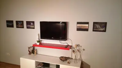 a flat screen tv on a white wall with pictures at Savinac apartman u srcu Beograda, Trg Slavija in Belgrade