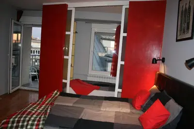 a bedroom with a bed with red walls and a window at Savinac apartman u srcu Beograda, Trg Slavija in Belgrade