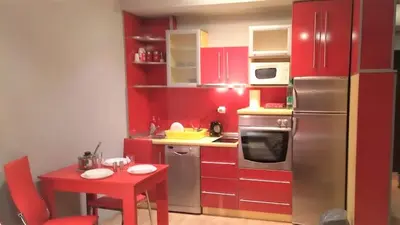 a kitchen with red cabinets and a red table with a red tableablish at Savinac apartman u srcu Beograda, Trg Slavija in Belgrade