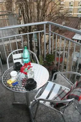 a table and chairs with a bottle and flowers on a balcony at Savinac apartman u srcu Beograda, Trg Slavija in Belgrade