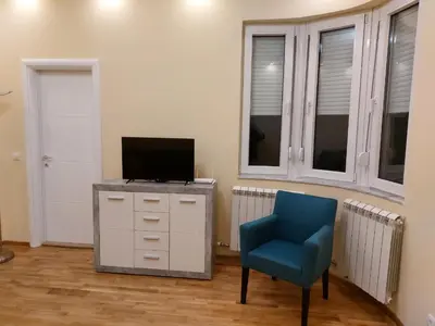 a living room with a tv and a blue chair at Jež in Belgrade