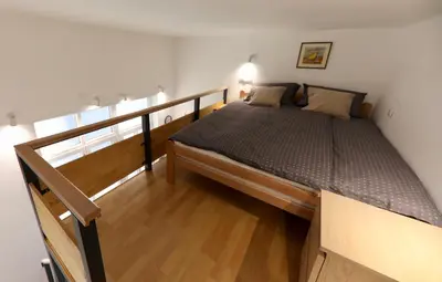 a small bedroom with a bed and a staircase at Central Ant Apartment in Belgrade