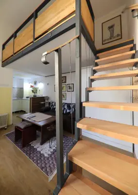 a loft bed in a room with a table at Central Ant Apartment in Belgrade