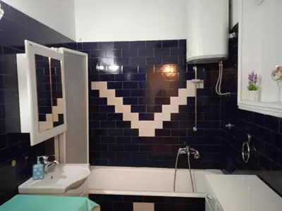 a bathroom with a black tiled wall and a bath tub at Bajloni lux in Belgrade