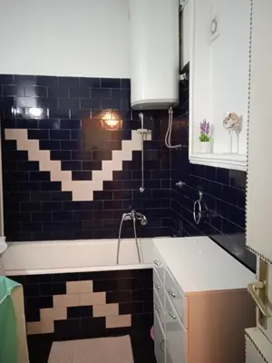 a bathroom with a tub and black tiles at Bajloni lux in Belgrade