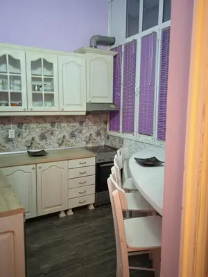 a kitchen with white cabinets and a table with chairs at Bajloni lux in Belgrade