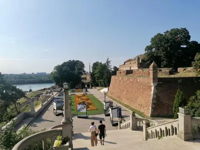two people walking down a street next to a wall at Central location for you in Belgrade