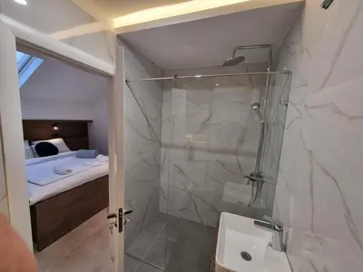 a bathroom with a shower and a sink and a bed at Parliament View Apartments in Belgrade