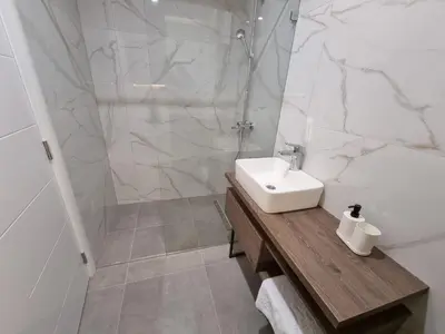 a white bathroom with a sink and a shower at Parliament View Apartments in Belgrade
