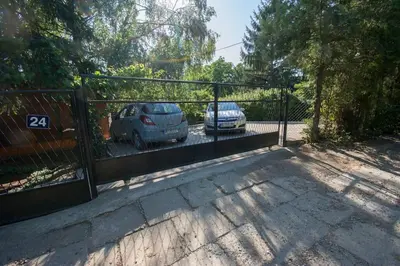two cars parked in a parking lot behind a gate at Happy house in Velika Remeta