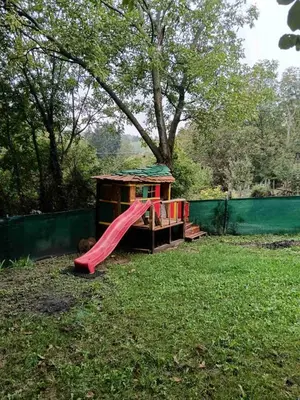 a playground with a red slide in the grass at Happy house in Velika Remeta