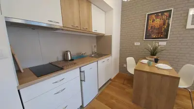 a kitchen with white cabinets and a wooden table at Apartments Delta A Blok - Savada in Belgrade