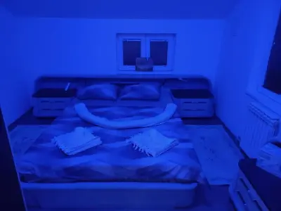 a bed in a room with a blue light at Apartmani Mladenović in Kijevo