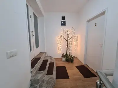 a hallway with a chandelier and a tree in it at Apartmani Mladenović in Kijevo