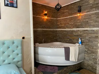 a bathroom with a tub and a blue chair at President app Arandjelovac in Arandjelovac