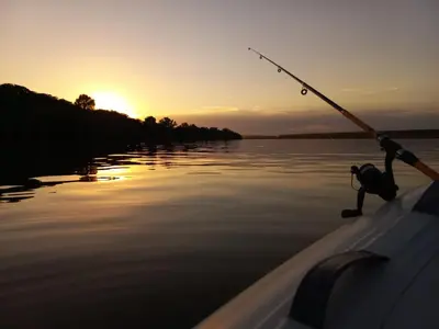 a person in a boat holding a fishing pole on the water at Bora kuće na reci in Belgrade