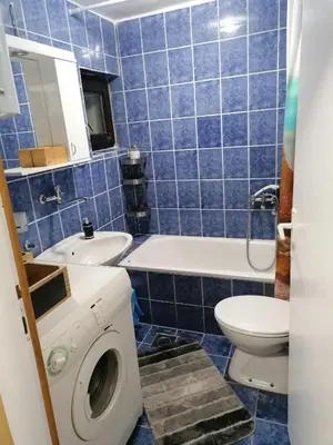 a blue tiled bathroom with a washing machine and a toilet at Vila Mila Fruška Gora in Velika Remeta