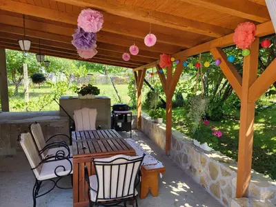 a wooden pergola with a table and chairs under it at Vila Mila Fruška Gora in Velika Remeta