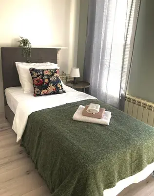 a bed with a green blanket and two towels on it at MiniCity Inn in Belgrade